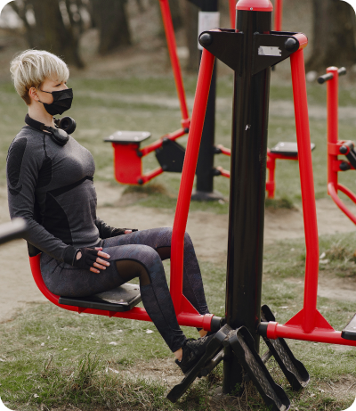 A woman sitting on a bench wearing a face mask while doing exercise