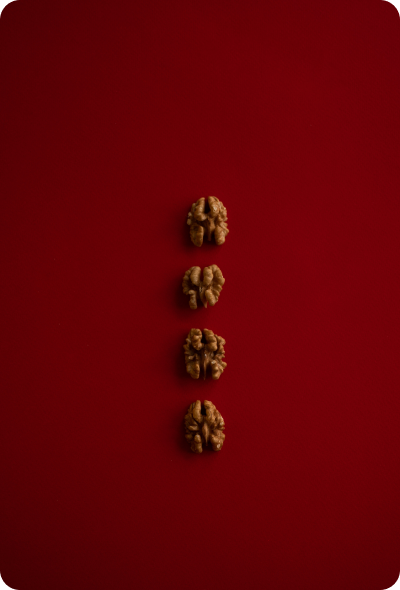 Four walnuts are arranged in a row on a red surface